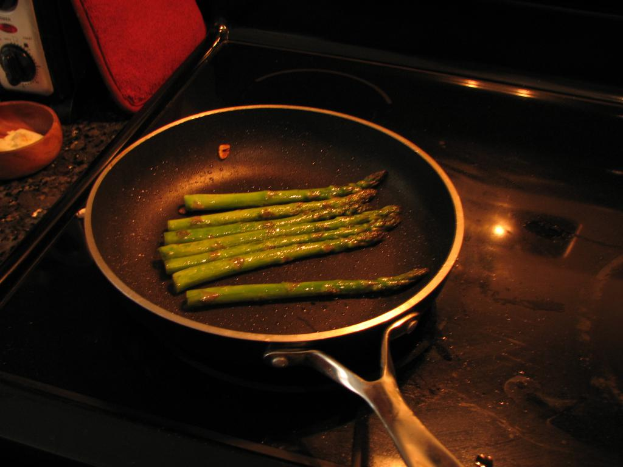 Ein Topf auf einem Herd mit einem Lebensmittel, eine Schüssel mit Gegenständen auf der linken Seite, ein Gerät und ein rotes Objekt.