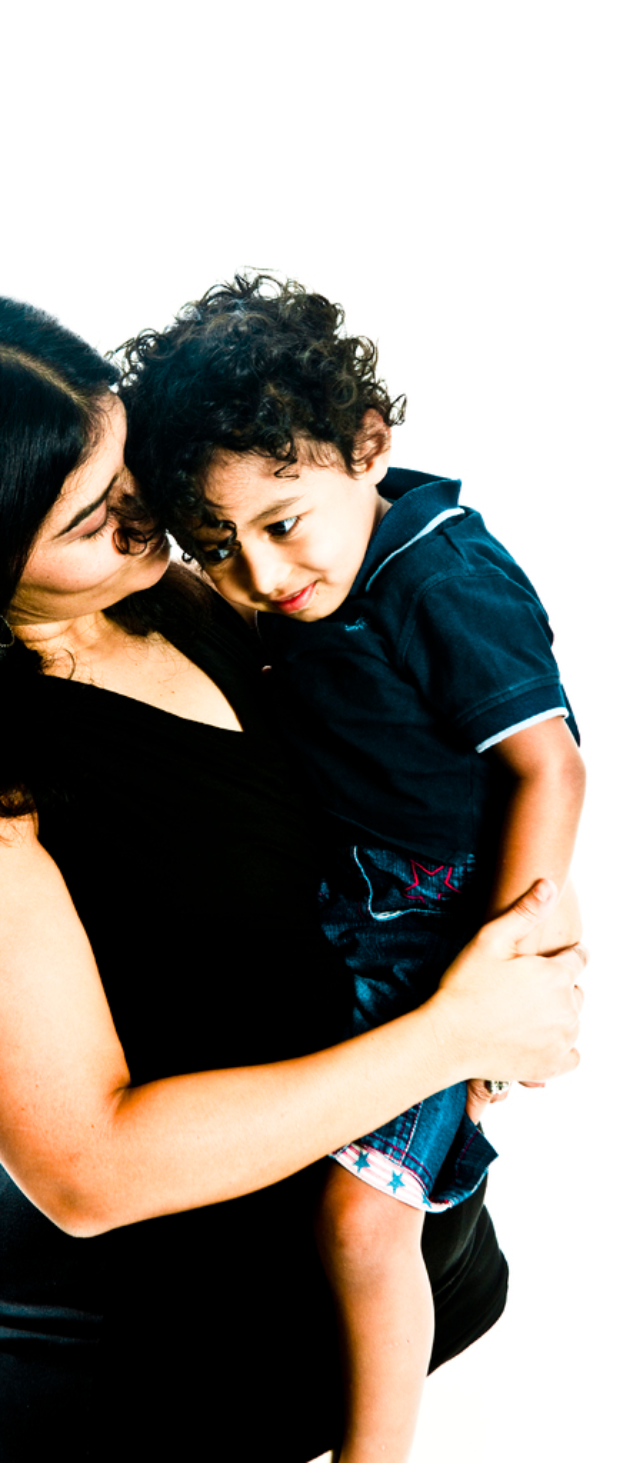 Eine Frau in einem schwarzen Kleid steht und hält ein Kind gegen einen weißen Hintergrund.