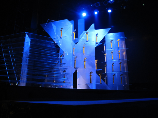 Eine dunkle Bühne mit minimaler Beleuchtung, die verstreute Objekte zeigt, die wahrscheinlich mit einer Preisverleihung zu tun haben.