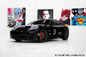 Ein schwarzer Nissan-Sportwagen steht vor Cartoon-Postern, mit einer kleinen Inschrift am unteren Rand des Bildes.