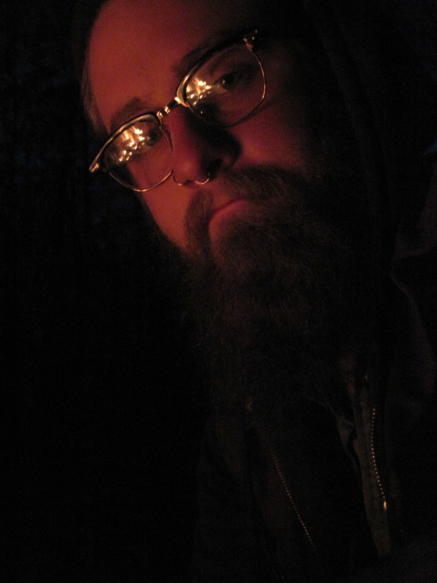 Ein Mann mit einem großen Bart und Brille posiert für die Kamera.