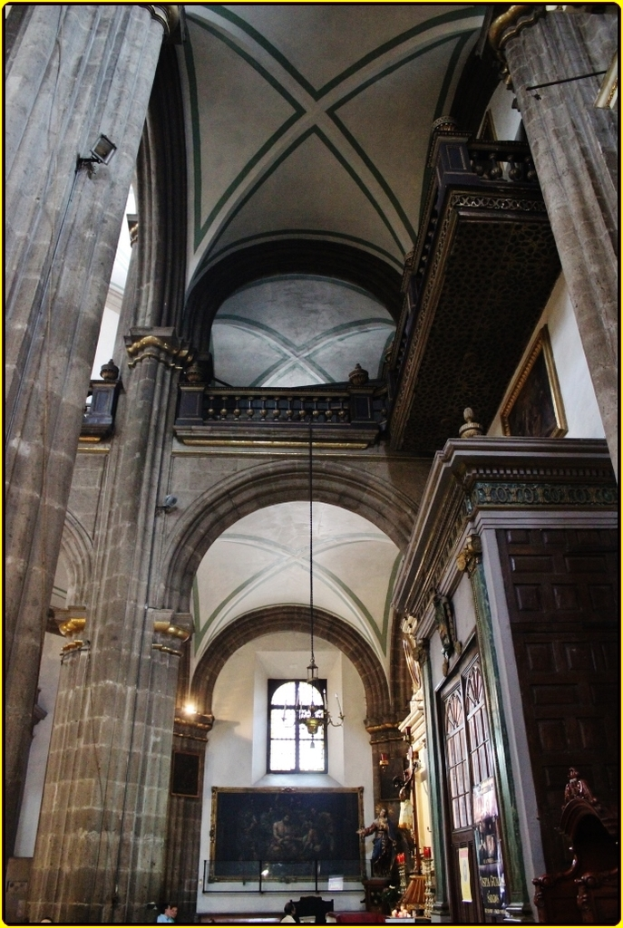 Ein Innenblick in ein Schloss mit Schränken, beleuchteten Säulen, Wandskulpturen, einem großen Rahmen und einer Deckenleuchte.