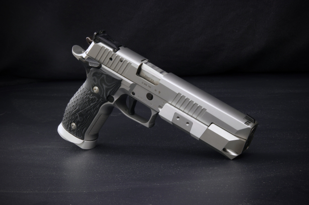 Sig Sauer P226 X-Five 9mm Pistole auf einer schwarzen Oberfläche vor einem schwarzen Hintergrund.