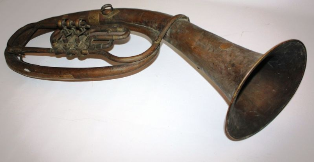 Alter Messinghorn mit glänzendem Finish, gebogener Hals und aufgeweiteter Schalltrichter, verziert mit kunstvollen Gravuren auf einem weißen Hintergrund.