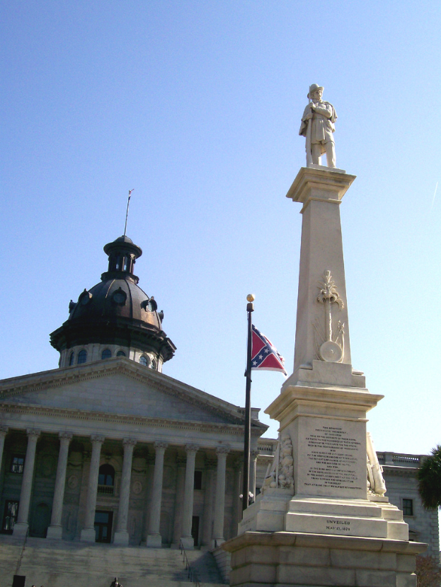 Eine Burg steht in der Mitte mit einem Friedhof, einer Statue, einem Pfahl und einer Flagge im Vordergrund, Treppen unten, ein Baum rechts und Himmel oben.