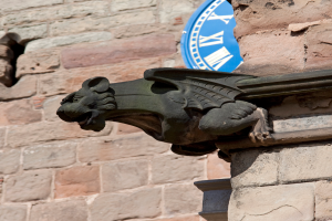 Eine historische Wand aus Stein und Ziegeln mit einer schwarzen Löwenstatue mit Flügeln.