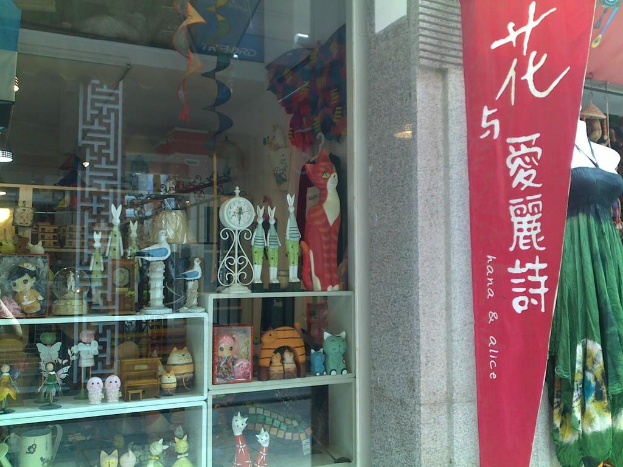 Eine Ausstellung mit verschiedenen Gegenständen, darunter ein Banner, eine Schaufensterpuppe und ein Traumfänger auf der linken Seite sowie ein Glasfenster, das Spielzeug, eine Uhr und einen Schrank auf der rechten Seite zeigt.