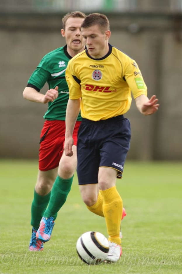 Zwei Männer beim Fussballspielen auf einem grünen Feld mit einem Ball, mit unscharfem Hintergrund und Text unten.