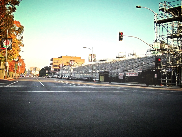 Eine Straße mit einem Verkehrszeichenmast und Equipment auf der rechten Seite, Warnschilder und mehrere Fahrzeuge auf der linken Seite und Bäume im Hintergrund.