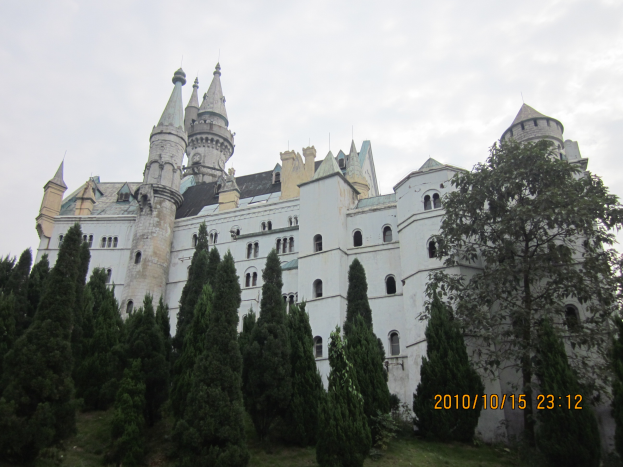 Neuschwanstein Burg in Deutschland, mit weißen Wänden und Fenstern, umgeben von Bäumen und Gras unter einem bewölkten Himmel, mit Text auf der rechten Seite des Bildes.