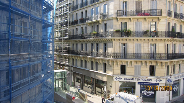 Großes Gebäude in Bau auf der linken Seite, mit einem Geschäft auf der unteren rechten Seite.