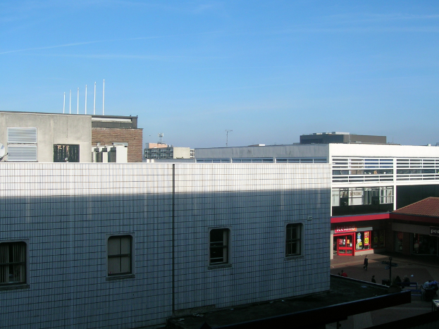 Eine Straßenszene mit Gebäuden und Geschäften, mit einigen Menschen, die dazwischen gehen.
