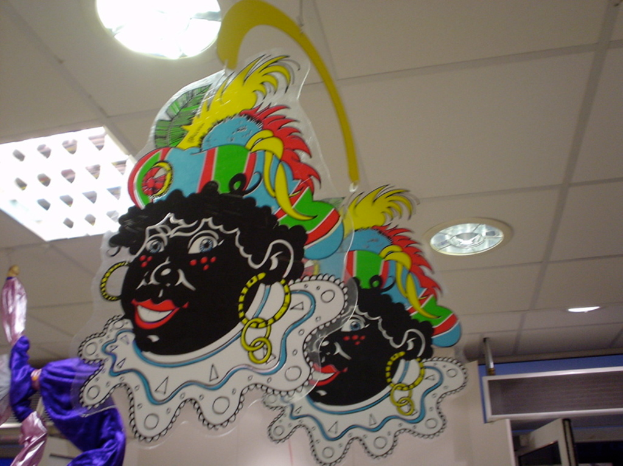 Mehrere Gemälde sind auf Gegenständen in einem Raum mit an der Decke angebrachten Lampen, einer Tür an der unteren rechten Seite und einem Gegenstand an der unteren linken Seite ausgestellt.