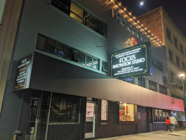 Außenansicht des Focus Innovation Studios in New York City bei Nacht, mit beleuchteten Gebäuden, Menschen auf dem Bürgersteig und dem Nachthimmel im Hintergrund.