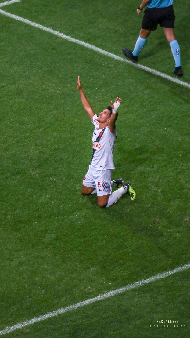Ein Fußballspieler in Uniform kniet auf dem Boden mit ausgestreckten Armen in Feierlaune.