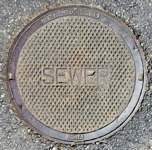 Metallschachtdeckel auf der Straße mit der Aufschrift "Kanal"