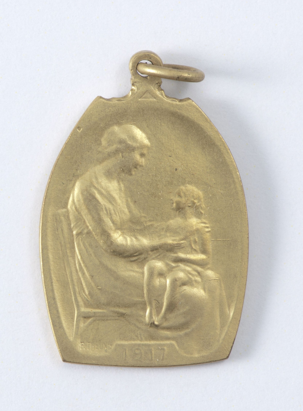 Goldmedaille mit einer Gravur einer Frau in einem weißen Kleid mit einem Dutt, die ein Kind hält, beide schauen sich mit Ausdrucken von Zärtlichkeit und Verwunderung an, beschriftet mit "Mutter und Kind."