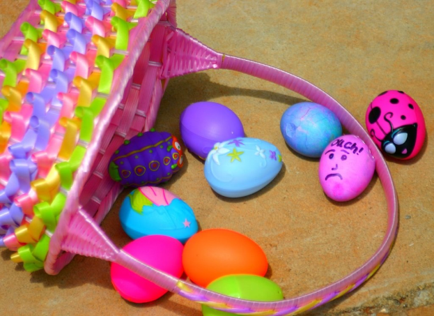 Ein geflochtener Korb mit mehreren farbenfrohen Ostereiern an einer Wand.