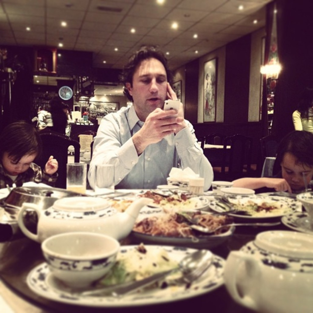 Ein Mann sitzt an einem Tisch mit einem Kessel, Teller, Löffel und Lebensmitteln.