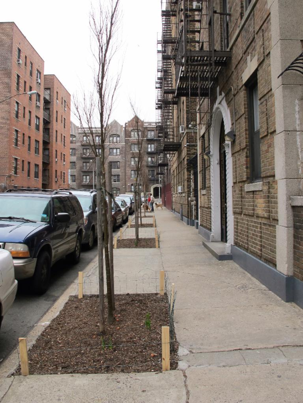 Eine spärlich besiedelte städtische Szene mit ein paar Autos und Gebäuden in der rechten Ecke und ein paar anderen Gebäuden in der linken Ecke.