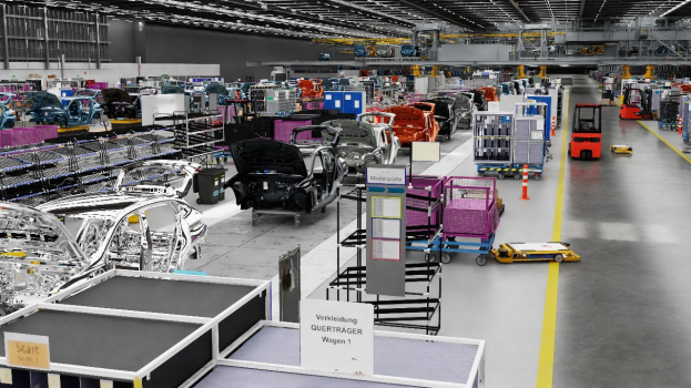 Gro├če Fabrikhalle mit mehreren Autos auf der Fl├Ąsse, metallische Strukturen links und rechts, Fahrzeuge auf dem Boden, eine Wand im Hintergrund und an der Decke angebrachte Lichter.