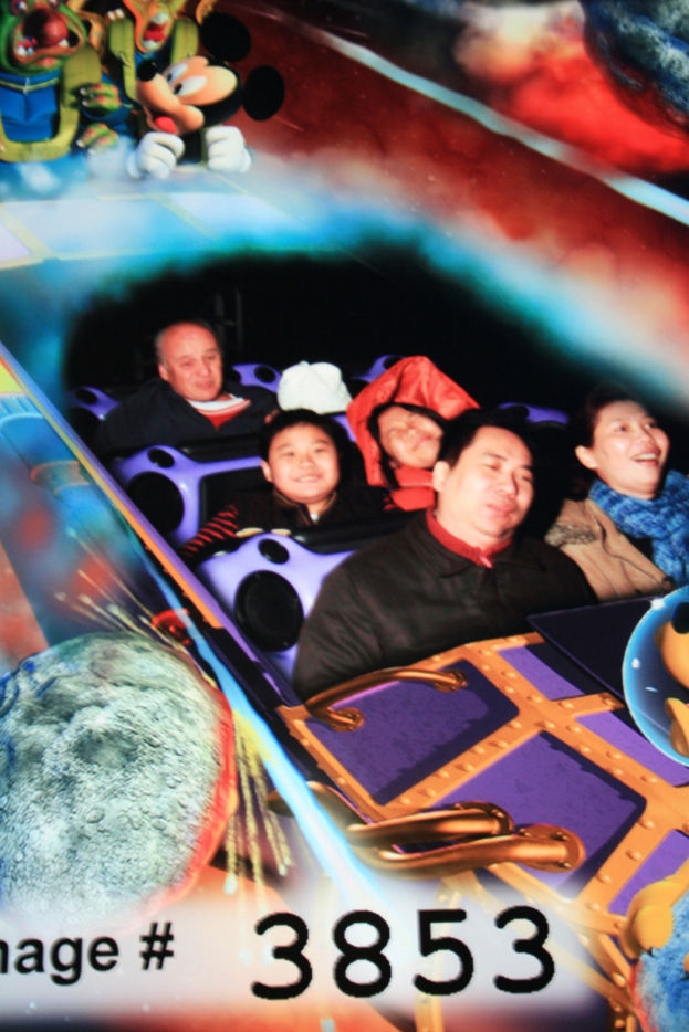 Menschen auf einer Achterbahn mit Mickey-Maus-Figuren im Hintergrund und Text unten.