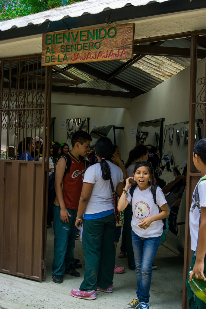 Ein Geschäft mit einer Eisenblechfassade und einer Schildertafel mit Text oben, mit Menschen drinnen.