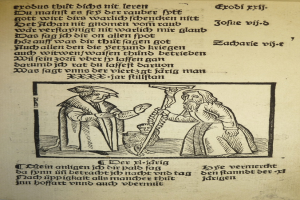 Eine gedruckte Seite in einer fremden Sprache mit zwei Männern im Hintergrund, möglicherweise aus einem Lehrbuch.