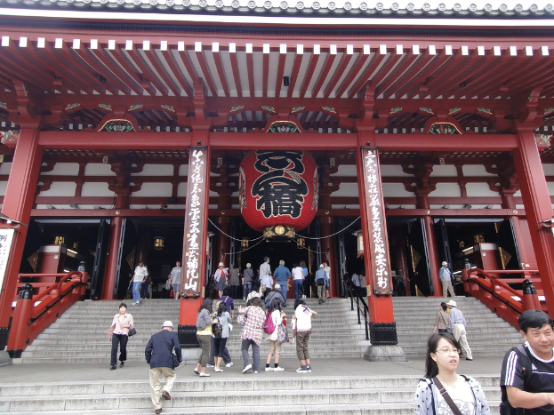 Eine Gruppe von Menschen vor einem Gebäude mit Säulen und Schildern.