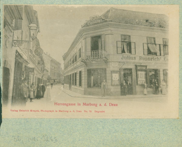 Ein altes Foto einer Stra√enszene in Marburg, Deutschland, mit Geb√§uden, Menschen und einem Himmel im Hintergrund, mit Text am unteren Rand des Bildes.