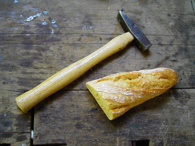 Ein Hammer und ein Lebensmittel sind auf einer hölzernen Plattform angeordnet.