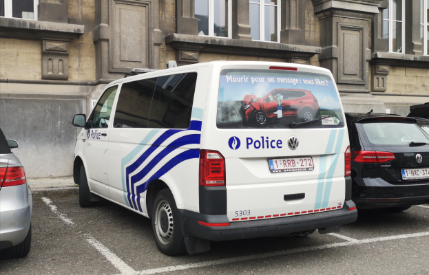 Ein Polizeiwagen steht auf einem Parkplatz neben einem Gebäude mit Fenstern, umgeben von anderen Fahrzeugen.
