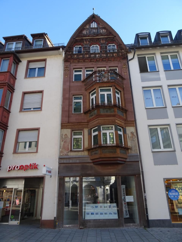 Gewerbebau mit vielen Fenstern zum Verkauf in Heidelberg, Deutschland, auf einer Straße mit einem klaren blauen Himmel im Hintergrund.