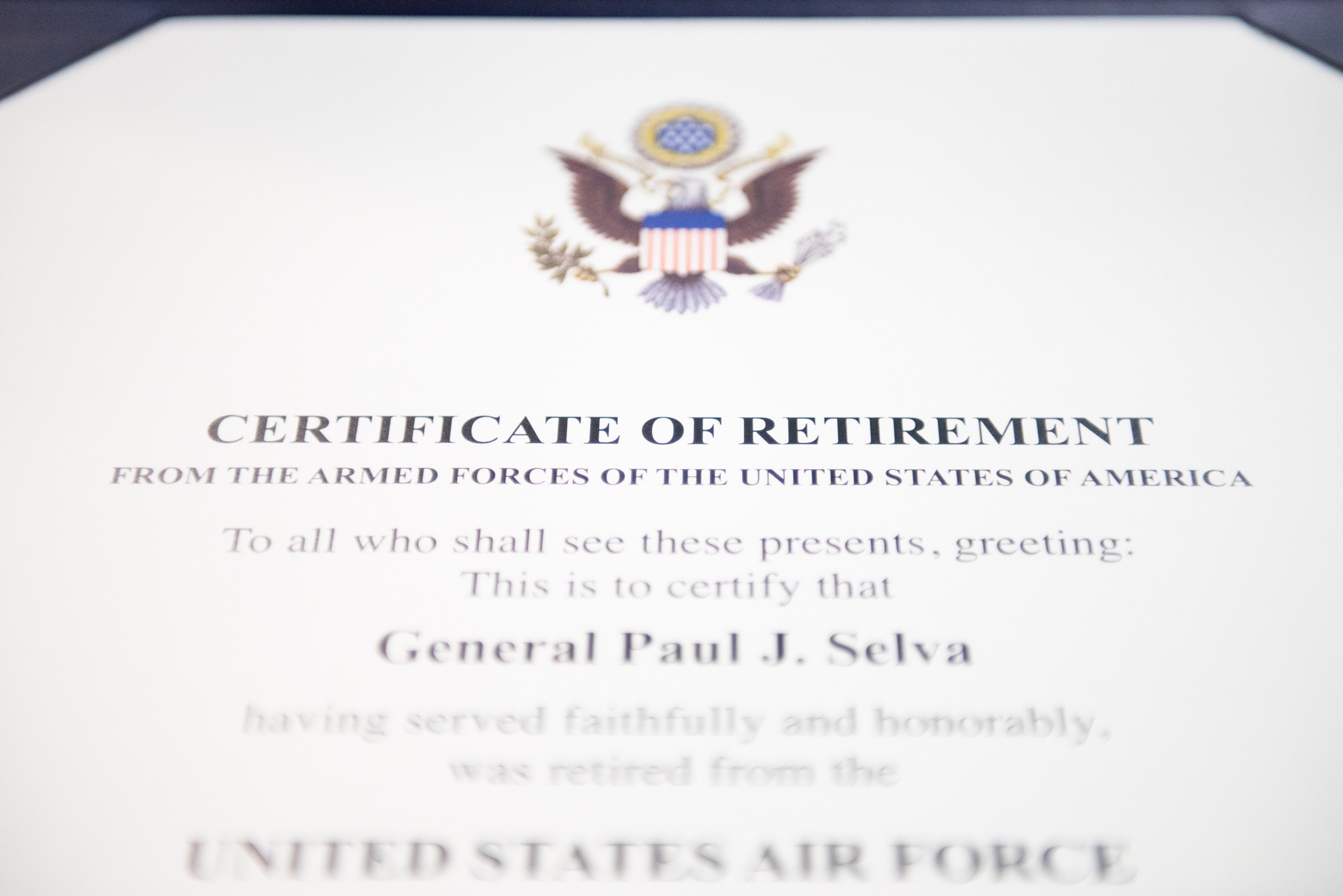 Rahmenurkunde für den Ruhestand von der United States Air Force mit blauem Rand, die ein zentrales Sternschild-Logo innerhalb eines Lorbeerkranzes und eine "Ruhestand"-Bannerschrift in schwarzer Tinte zeigt.