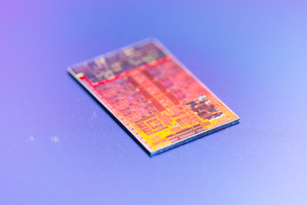 Nahaufnahme eines Mikrochips auf einer blauen Oberfläche, identifiziert als der neue Intel-Prozessor.