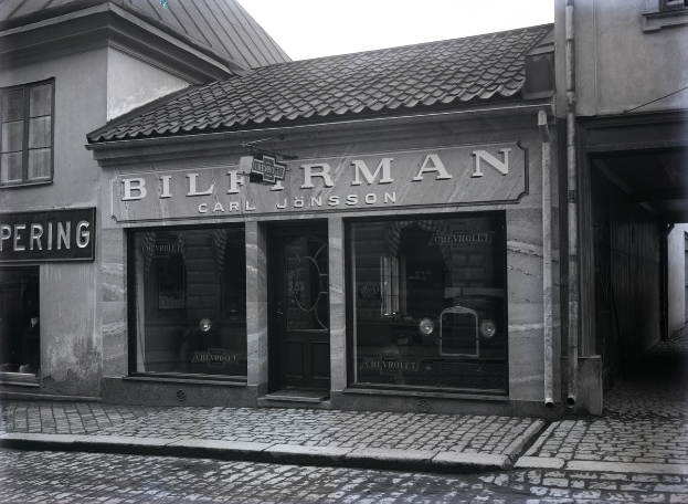 Ein Schwarz-Weiß-Foto eines Gebäudes mit einer "Bilferman"-Aufschrift, Fenstern, einer Tür und Tafeln mit Text, mit einer Straße unten.