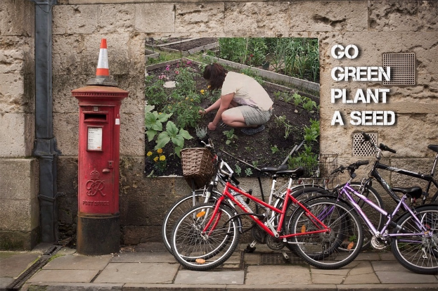 Fahrräder in der Nähe eines Briefkastens mit einer Sicherheitstüte auf der Oberseite, einem Plakat an einer Wand im Hintergrund und einem Weg am unteren Rand des Bildes.