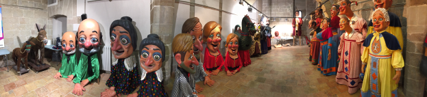 Eine Gruppe von Menschen in einem Raum mit einer Tafel links, Puppen in der Mitte und ein paar Personen rechts.