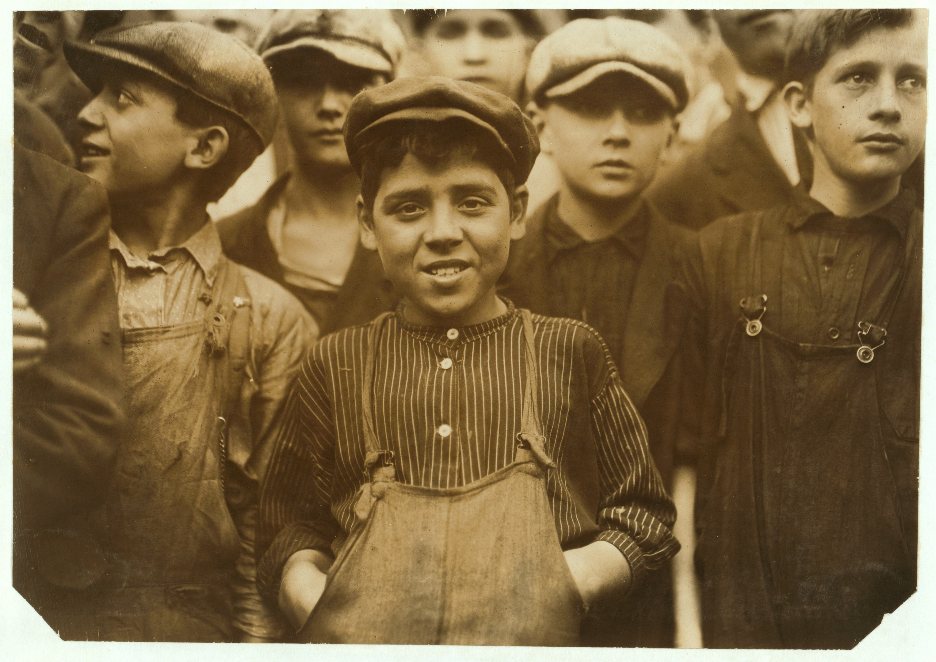 Schwarzes und weißes Foto einer Gruppe junger Jungs, die nebeneinander stehen, jeder trägt eine Mütze.